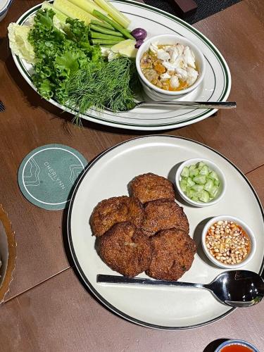 two plates of food with meat and vegetables on a table at Cherlynn Resort in Ban Gaeng Cho