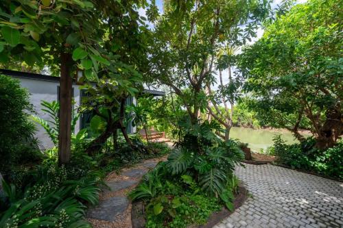 a garden with trees and a brick walkway at Cherlynn Resort in Ban Gaeng Cho
