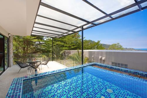 a swimming pool with a view of a house at Sea View & Tropical Bliss - 2BR Villa Natural Touch A4 at Kamala Hill in Kamala Beach