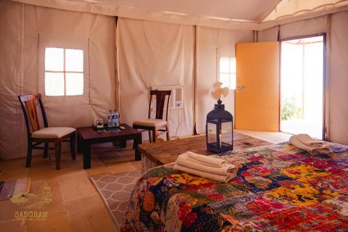 a bedroom with a bed and a table and chairs at Sangram Desert camp in Jaisalmer