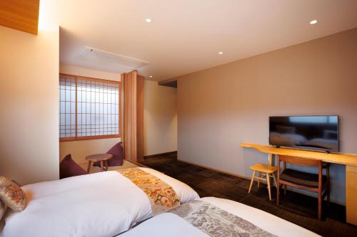 a hotel room with two beds and a desk at Hotel Ethnography Kiyomizu Gojo in Kyoto