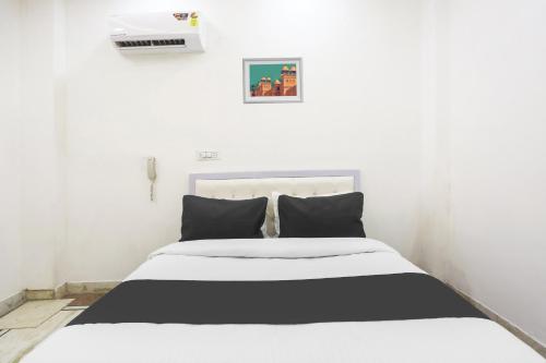 a white bedroom with a black and white bed at Hotel O Golden Key Rohini in New Delhi