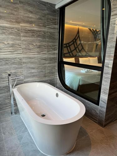 a bath tub in a bathroom with a large mirror at S3 Ayutthaya Hotel in Phra Nakhon Si Ayutthaya