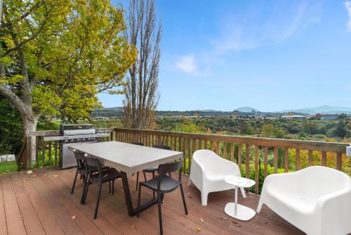a wooden deck with a table and chairs and a grill at Tūī Cottage in Kinloch