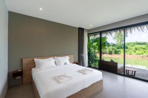 a bedroom with a large bed and a large window at Cherlynn Resort in Ban Gaeng Cho