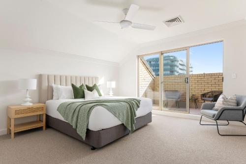 ein weißes Schlafzimmer mit einem Bett und einem Stuhl in der Unterkunft Urban Rest Bondi Beach in Sydney