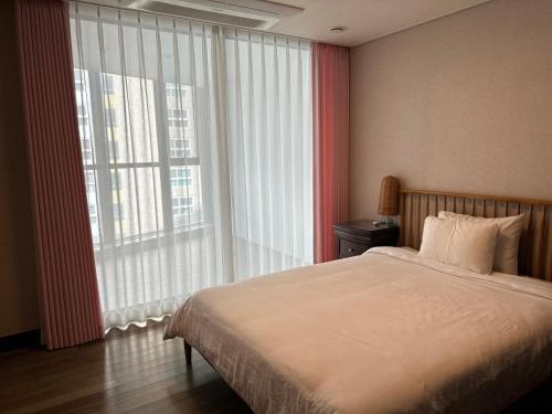 a bedroom with a bed and a large window at Haeundae Luxury House in Busan
