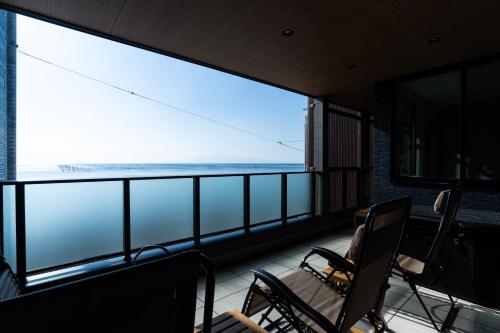 ein Balkon mit Stühlen und Blick auf das Meer in der Unterkunft みらいステイKawachi in Kumamoto