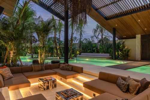 a living room with a couch and a swimming pool at Villa Baratega - Dreamy Urban Tropical 6BR Villa for Large Group in Kerobokan