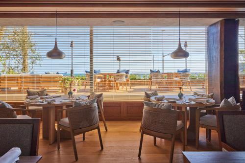 a restaurant with tables and chairs and a large window at UMITO Kamakura Koshigoe in Kamakura