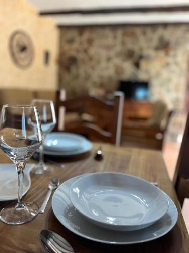 a wooden table with plates and wine glasses on it at Tres deseos in Montefrío