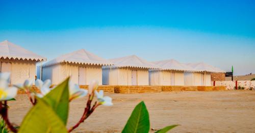 a row of huts with white flowers in front of them at DESERT OVERNIGHT LUXURY CAMP & ReSORT in Jaisalmer