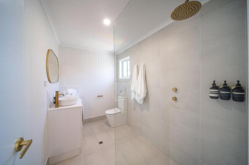 a white bathroom with a shower and a toilet at ILUKA Luxe accommodation, relaxed coastal vibe in Aldinga Beach