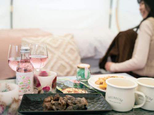 a table with a plate of food and glasses of wine at くじゅう花公園 グランピングパーク花と星 in Kuju