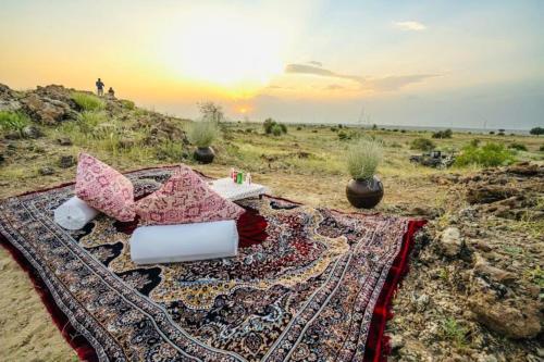 a rug on the beach with the sunset in the background at DESERT OVERNIGHT LUXURY CAMP & ReSORT in Jaisalmer