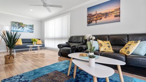 a living room with a couch and a table at Alka Beach House in Callala Beach