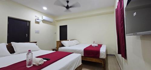 a hotel room with two beds and a flat screen tv at Sun Residency Tvm in Tiruvannāmalai