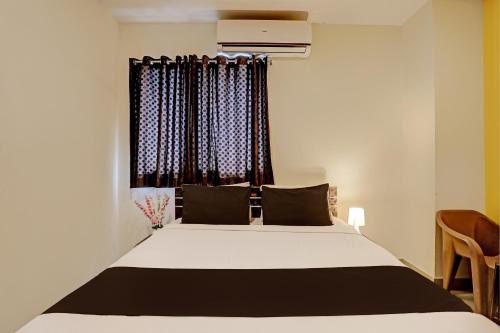 a bedroom with a bed and a window with curtains at Capital O Saharsh Grand Near Shilparamam in Hyderabad