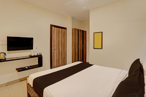 a bedroom with a bed and a flat screen tv at Capital O Saharsh Grand Near Shilparamam in Hyderabad