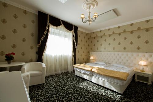 a bedroom with a bed and a chair and a window at Conacul din Ardeal in Braşov
