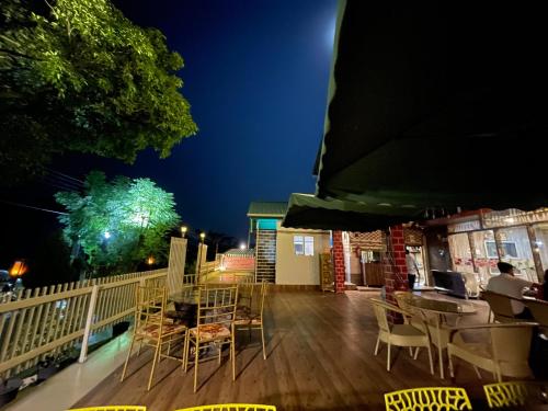 a deck with chairs and tables at night at Paradise Woodland Resort Chintpurni in Bharwain