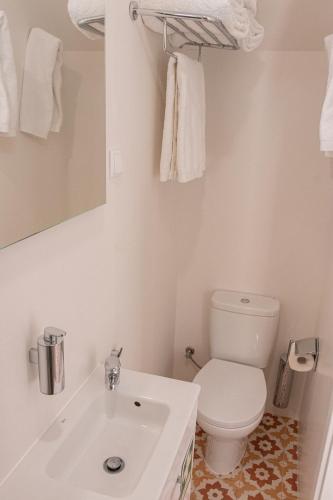 a white bathroom with a toilet and a sink at Casa Torta in Setúbal