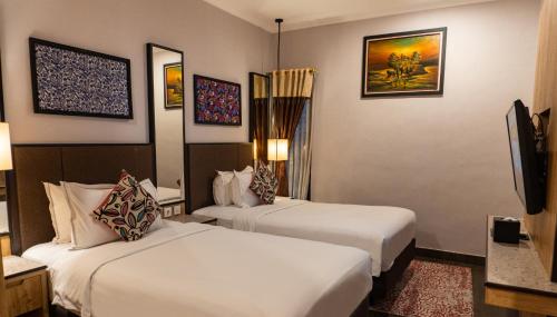 a hotel room with two beds and a flat screen tv at Grand Sunshine Resort & Convention in Bandung