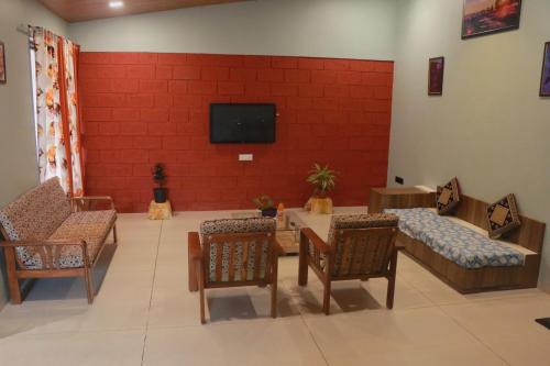 a waiting room with tables and chairs and a flat screen tv at Orchid View Villa Mahabaleshwar 2 Bhk Villa in Mahabaleshwar