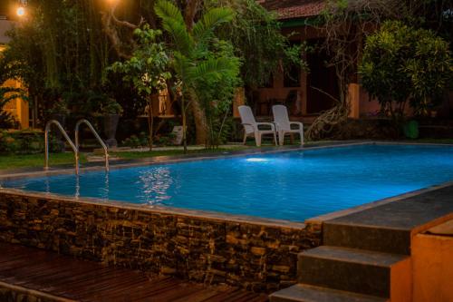 a swimming pool in a yard with chairs around it at Monkey villa in Hikkaduwa