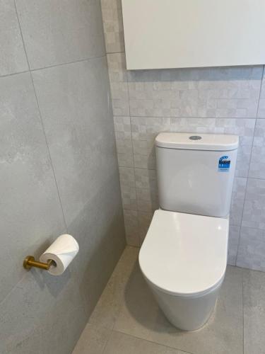 a bathroom with a toilet and a roll of toilet paper at White Rabbit Mountain Guest House in Mount Beauty