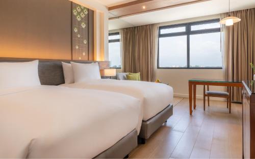 a hotel room with two beds and a desk at Dusit Princess Chiang Mai in Chiang Mai