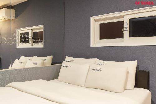 a room with a bed with white pillows and mirrors at Bed Station in Incheon