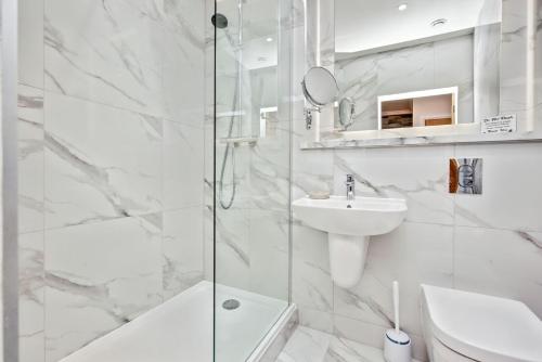 a white bathroom with a shower and a sink at Spectacular 2 bed, 2 bath in Edinburgh City Centre in Edinburgh