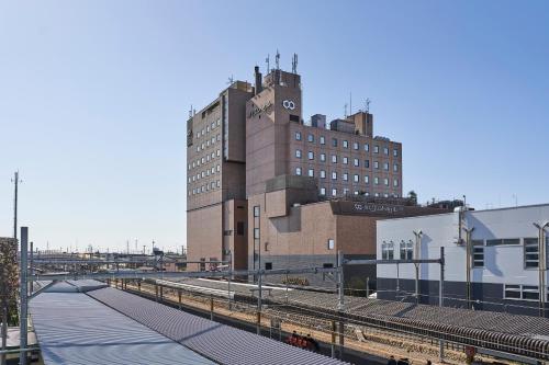 a building with a clock tower next to a train station at Saitama Grand Hotel Honjo in Honjo