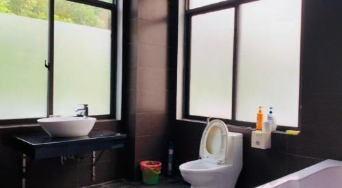 a bathroom with a toilet and a sink and windows at Villa Owner tại khu nghỉ dưỡng sinh thái Đại Lải Resort in Ngọc Quang