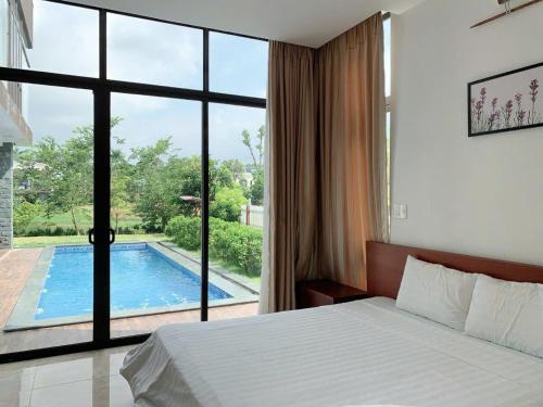 a bedroom with a bed and a view of a swimming pool at Villa Owner tại khu nghỉ dưỡng sinh thái Đại Lải Resort in Ngọc Quang