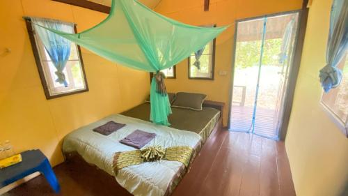 a bedroom with a bed with a green canopy at Eco Bungalow in Ko Phayam