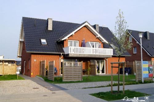 a red brick house with a balcony on a street at 01 Sommerhus Esbjerg DHH mit Sauna und Whirlpool in Burg auf Fehmarn