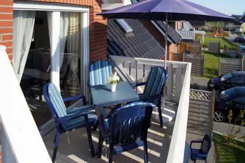 a table with chairs and an umbrella on a deck at 01 Sommerhus Esbjerg DHH mit Sauna und Whirlpool in Burg auf Fehmarn