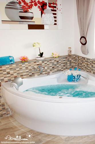 a bath tub with blue water in a bathroom at 01 Sommerhus Femø Wellness EG An der Reiterkoppel 3a in Burg auf Fehmarn