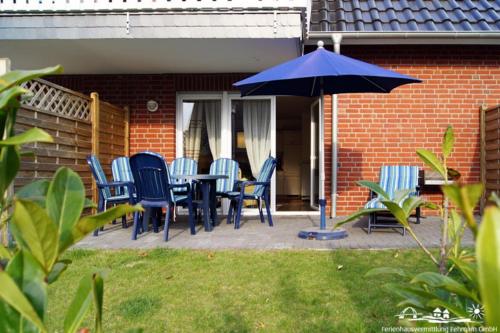 a patio with a table and chairs and an umbrella at 01 Sommerhus Femø Wellness EG An der Reiterkoppel 3a in Burg auf Fehmarn