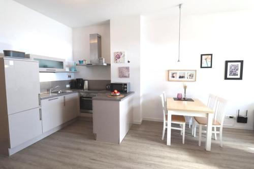 a kitchen with white cabinets and a table and a dining room at 02 Ferienwohnung Strandnest 1 Strandburg App.0.2 rechts in Burgtiefe auf Fehmarn 