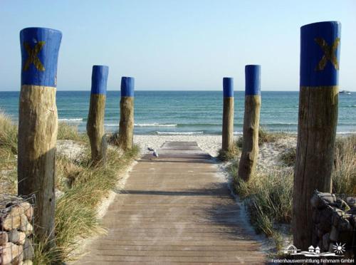a wooden path leading to a beach with the ocean at 02 Ferienwohnung Strandnest 1 Strandburg App.0.2 rechts in Burgtiefe auf Fehmarn 
