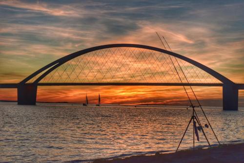 a bridge over the water with a sunset in the background at 02 Ferienwohnung Strandnest 1 Strandburg App.0.2 rechts in Burgtiefe auf Fehmarn 