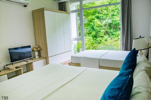 a bedroom with two beds and a tv and a window at Villa Owner tại khu nghỉ dưỡng sinh thái Đại Lải Resort in Ngọc Quang