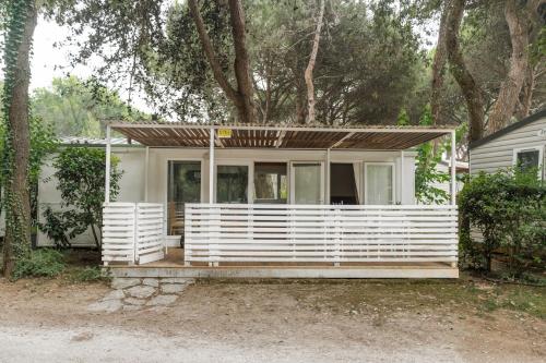 a small white house with a porch and trees at Club del Sole Jesolo Family Resort in Lido di Jesolo