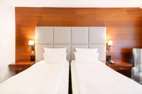 two beds in a hotel room with a chair at Hilton Frankfurt Gravenbruch in Gravenbruch
