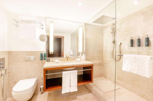 a bathroom with a toilet and a sink and a shower at Hilton Frankfurt Gravenbruch in Gravenbruch