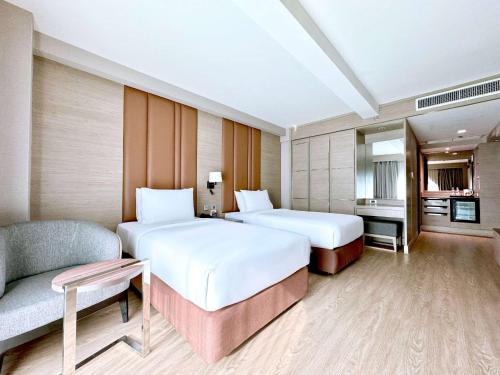 a hotel room with two beds and a couch at Ramada Sukhumvit Soi Eleven in Bangkok