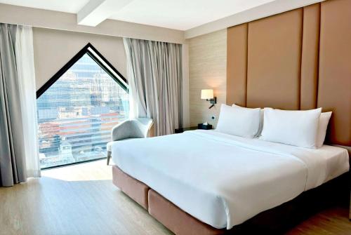 a large bed in a hotel room with a large window at Ramada Sukhumvit Soi Eleven in Bangkok